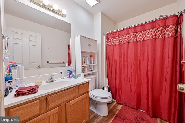 bathroom with a shower with shower curtain, hardwood / wood-style floors, vanity, and toilet