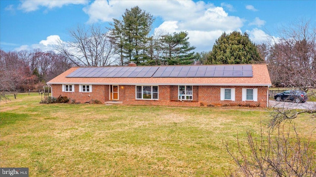 ranch-style house featuring solar panels and a front lawn