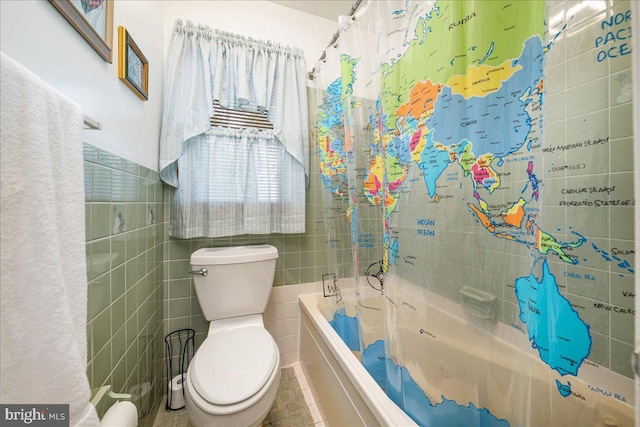 bathroom featuring tile patterned floors, shower / bath combo with shower curtain, tile walls, and toilet