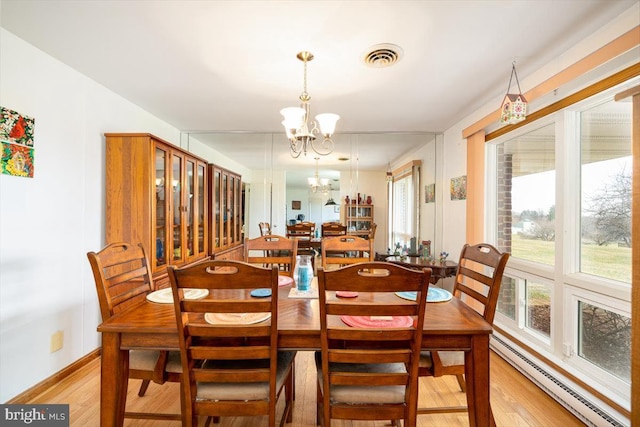 dining area with baseboard heating, light hardwood / wood-style floors, and a notable chandelier