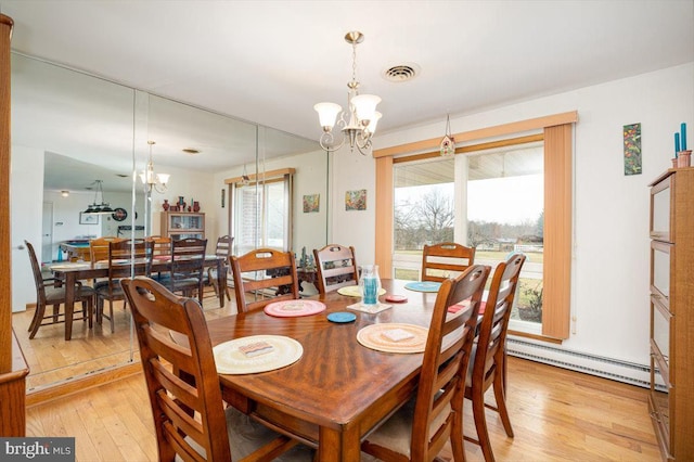 dining room featuring light hardwood / wood-style floors, a baseboard radiator, a healthy amount of sunlight, and a notable chandelier