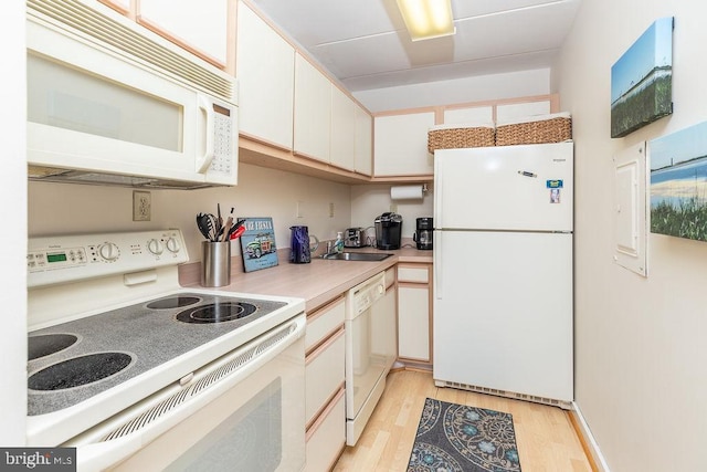 kitchen featuring white appliances, white cabinetry, and light hardwood / wood-style flooring