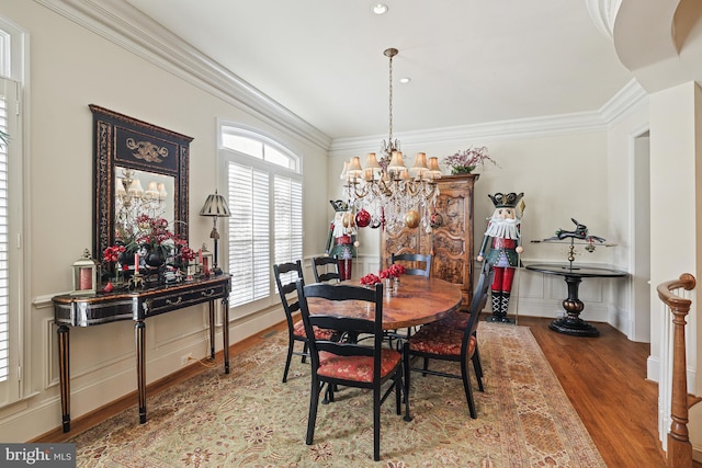 dining space with hardwood / wood-style floors, ornamental molding, and an inviting chandelier