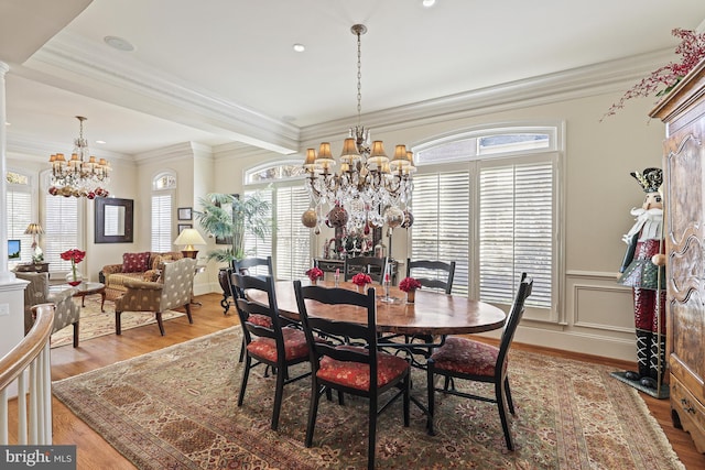 dining area with hardwood / wood-style flooring, ornamental molding, and an inviting chandelier