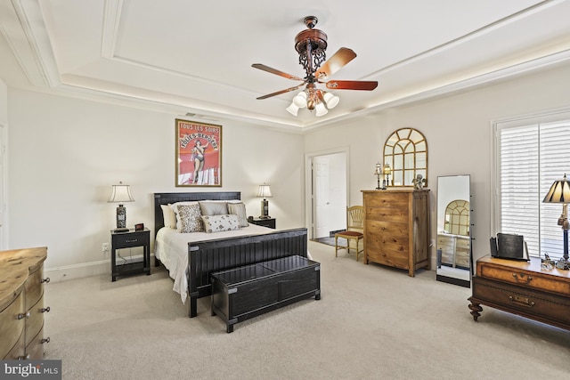 bedroom with a raised ceiling, ceiling fan, and light colored carpet