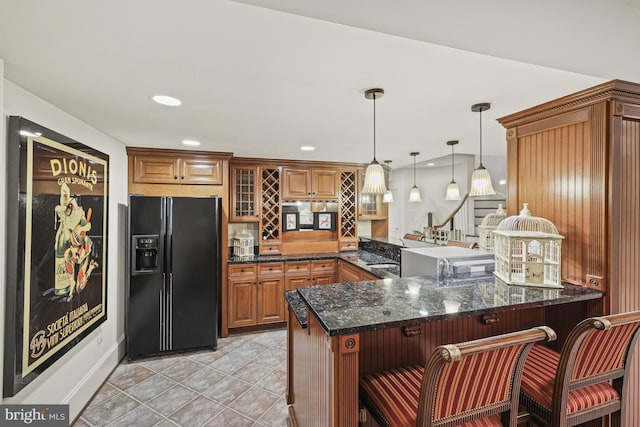 kitchen with kitchen peninsula, a kitchen breakfast bar, black refrigerator with ice dispenser, and hanging light fixtures