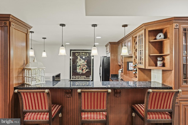 bar featuring refrigerator, hanging light fixtures, and dark stone countertops