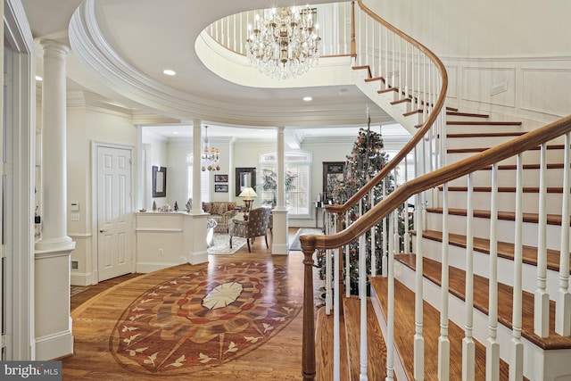 entryway featuring hardwood / wood-style floors, decorative columns, ornamental molding, and a tray ceiling