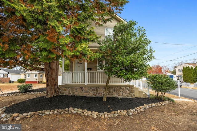 view of property hidden behind natural elements featuring a porch