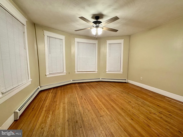 empty room featuring ceiling fan, light wood-type flooring, and a baseboard radiator