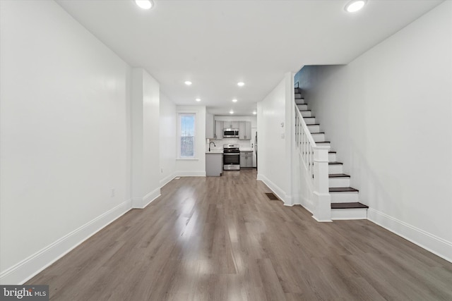 unfurnished living room featuring sink and light hardwood / wood-style flooring