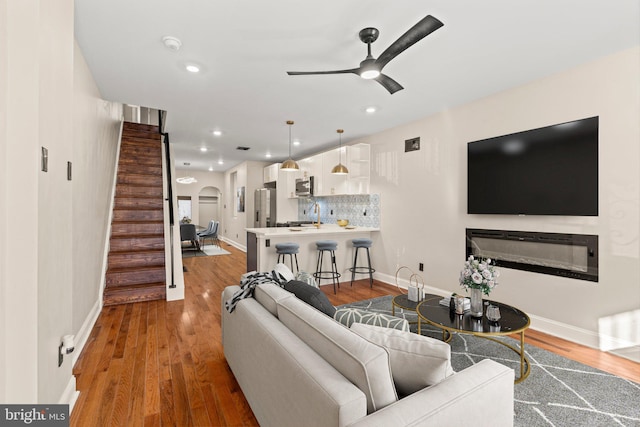 living room featuring hardwood / wood-style floors, ceiling fan, and sink