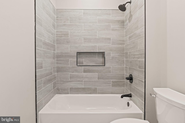 bathroom featuring tiled shower / bath combo and toilet