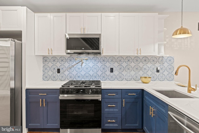 kitchen with pendant lighting, blue cabinets, sink, white cabinetry, and stainless steel appliances