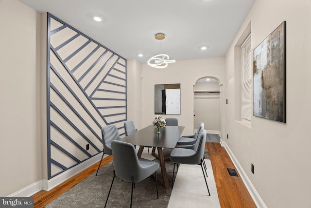 dining space with hardwood / wood-style floors and a notable chandelier