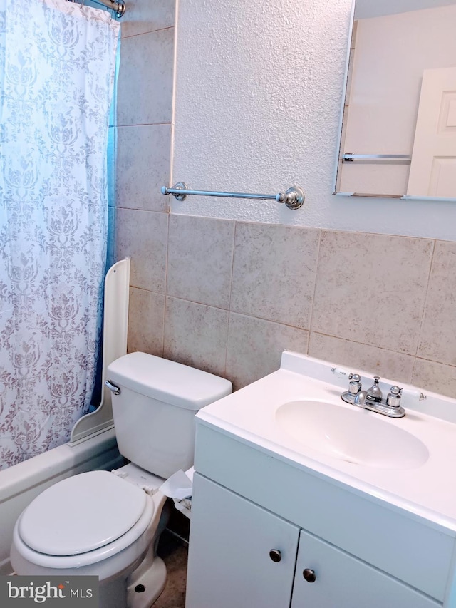 full bathroom featuring vanity, shower / bath combination with curtain, toilet, and tile walls