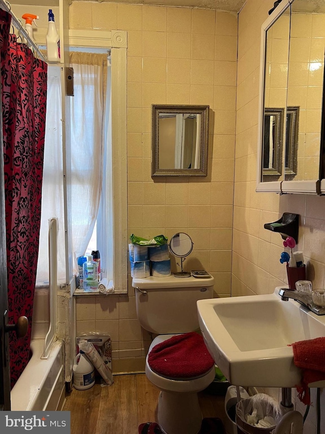 full bathroom with shower / tub combo, sink, tile walls, hardwood / wood-style floors, and toilet