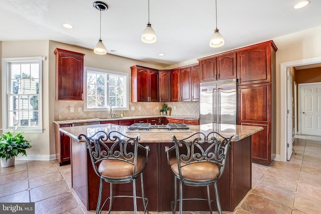 kitchen with light stone countertops, a healthy amount of sunlight, a center island, and stainless steel appliances