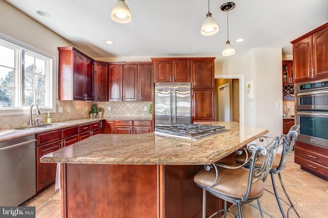 kitchen with stainless steel appliances, a kitchen island, hanging light fixtures, and sink