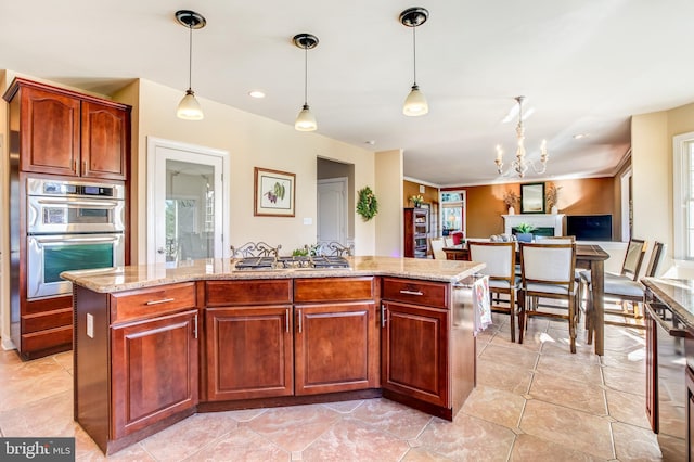 kitchen with stainless steel double oven, hanging light fixtures, a notable chandelier, and an island with sink