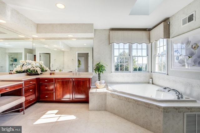 bathroom featuring tile patterned flooring, vanity, and a relaxing tiled tub