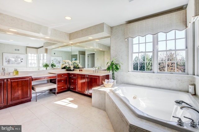 bathroom featuring tile patterned flooring, vanity, and tiled bath