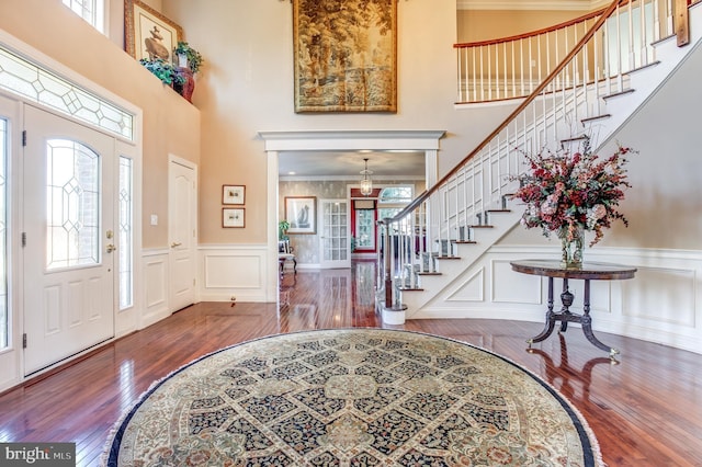 foyer featuring hardwood / wood-style floors, a towering ceiling, and ornamental molding