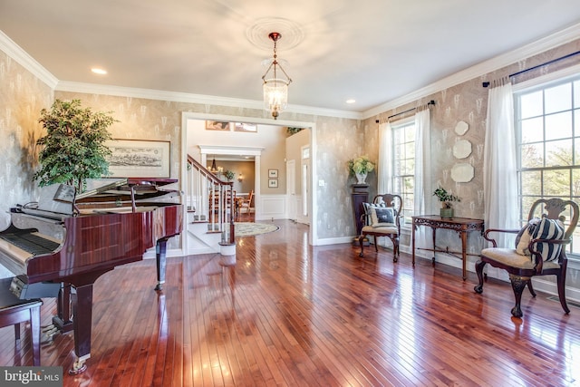 living area featuring hardwood / wood-style flooring, ornamental molding, and an inviting chandelier