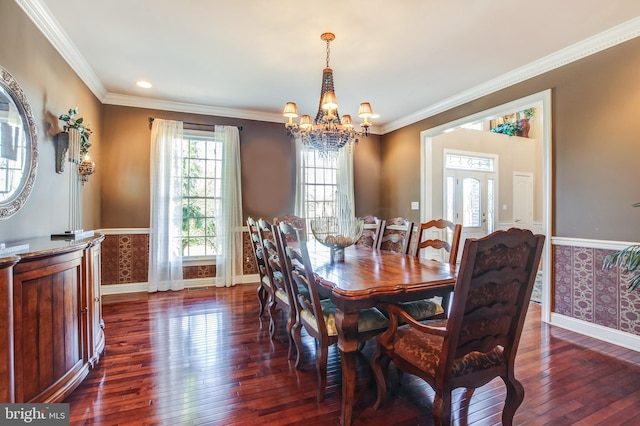 dining space with dark hardwood / wood-style flooring, ornamental molding, and an inviting chandelier