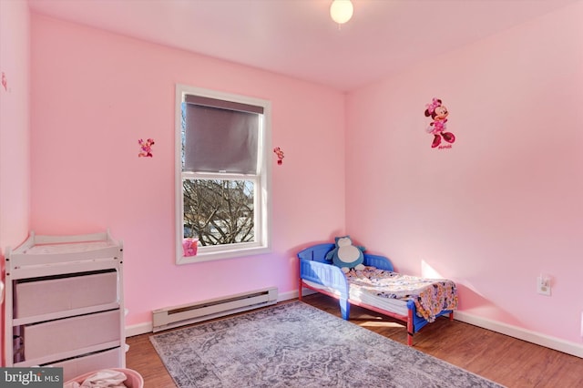 bedroom featuring wood-type flooring and a baseboard heating unit