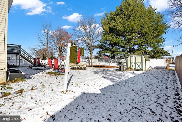 yard covered in snow with a storage shed