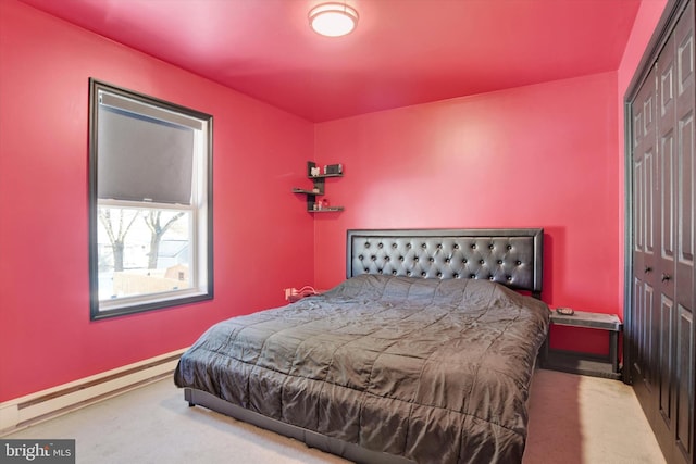 bedroom with a closet, light colored carpet, and a baseboard radiator