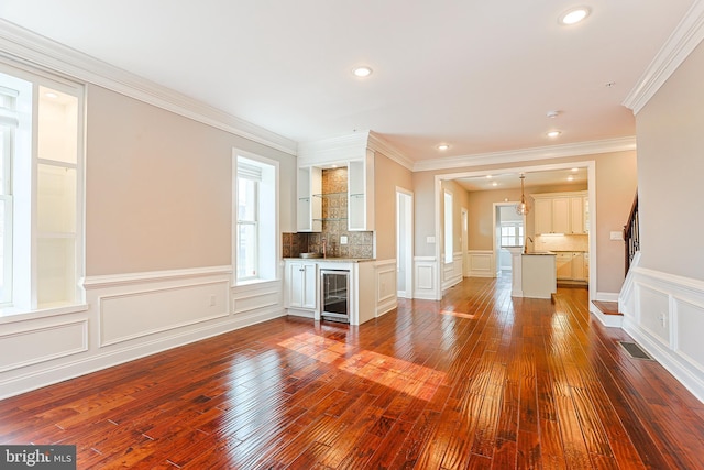 unfurnished living room featuring a healthy amount of sunlight, wine cooler, and dark hardwood / wood-style floors