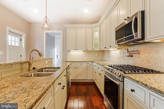 kitchen featuring appliances with stainless steel finishes, dark hardwood / wood-style floors, pendant lighting, sink, and light stone counters