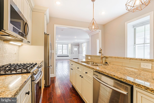 kitchen featuring sink, dark hardwood / wood-style flooring, hanging light fixtures, light stone counters, and stainless steel appliances