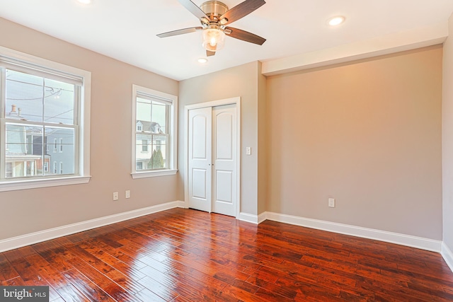 unfurnished bedroom with dark wood-type flooring, ceiling fan, and a closet