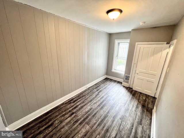 interior space with dark hardwood / wood-style flooring and wooden walls