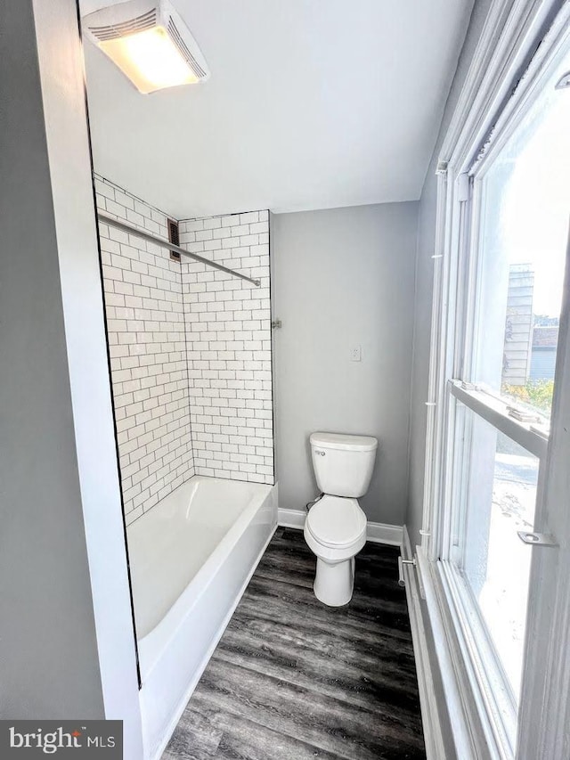 bathroom with wood-type flooring, tiled shower / bath, and toilet