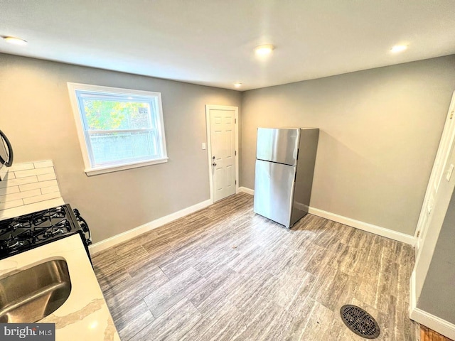 kitchen with stainless steel fridge and light hardwood / wood-style floors