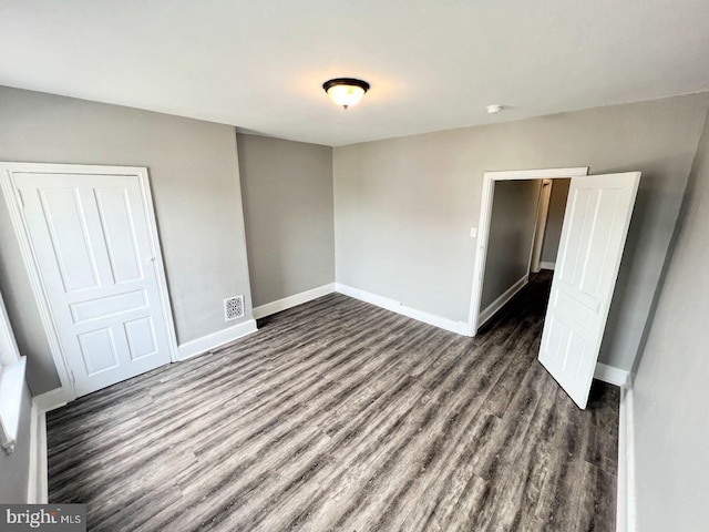 unfurnished bedroom with dark wood-type flooring