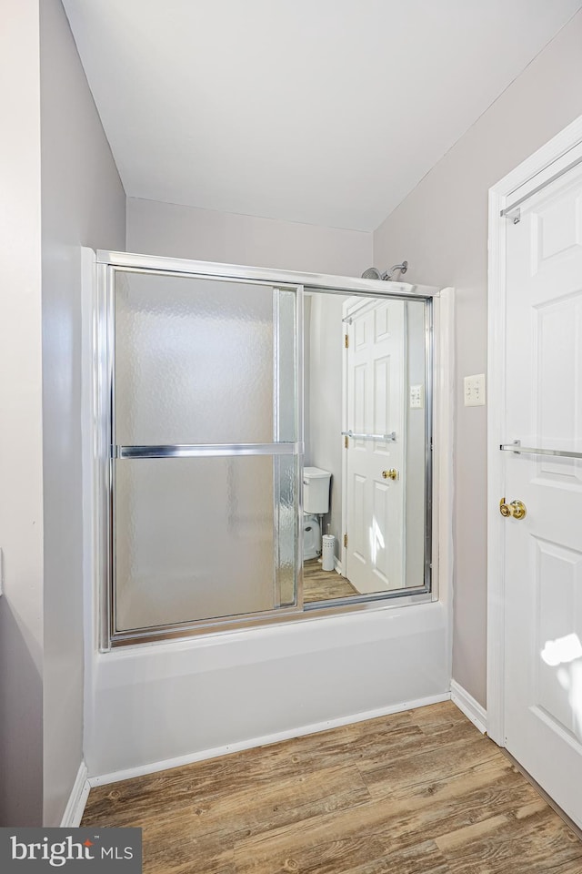 bathroom with hardwood / wood-style floors and enclosed tub / shower combo