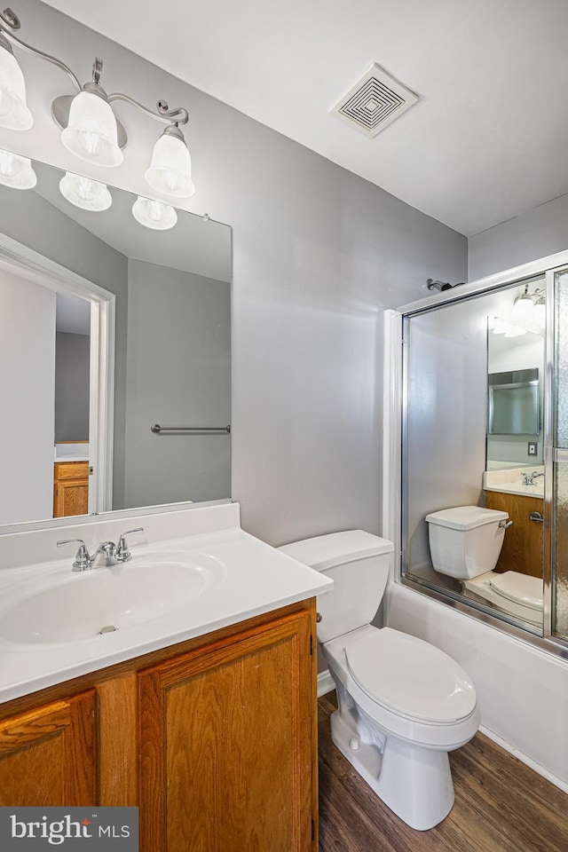 full bathroom featuring toilet, vanity, combined bath / shower with glass door, and hardwood / wood-style flooring