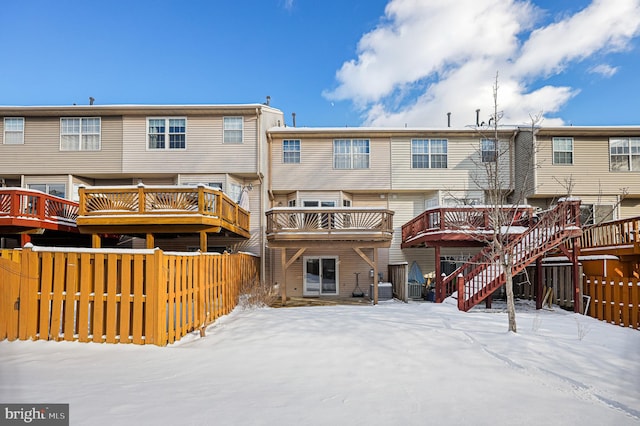 snow covered rear of property featuring central AC