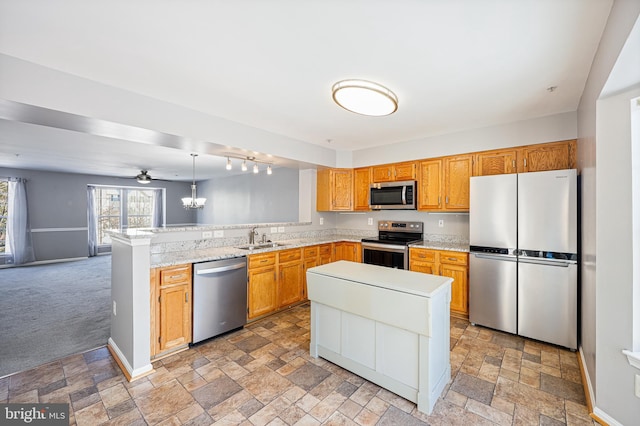 kitchen with kitchen peninsula, stainless steel appliances, light colored carpet, sink, and pendant lighting