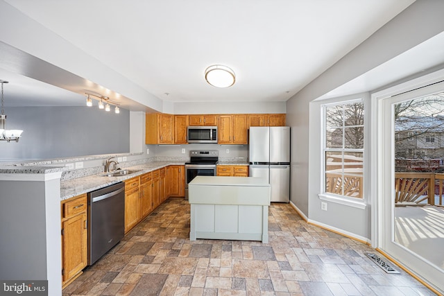 kitchen with sink, stainless steel appliances, a chandelier, pendant lighting, and a kitchen island