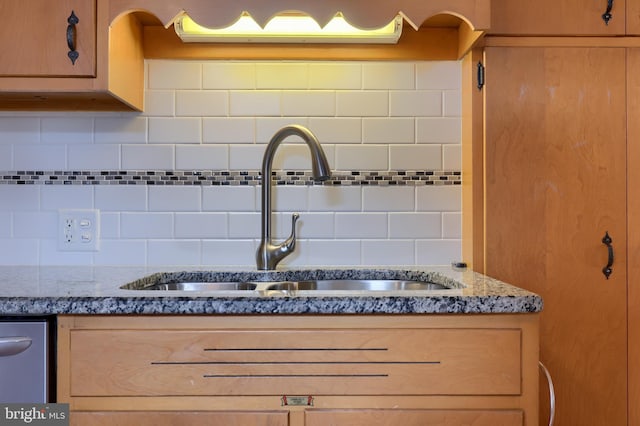 interior details featuring light stone countertops, backsplash, stainless steel dishwasher, and sink