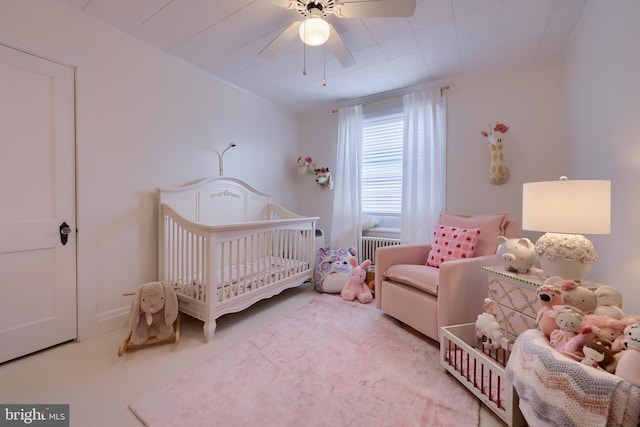 carpeted bedroom featuring ceiling fan, a crib, and radiator