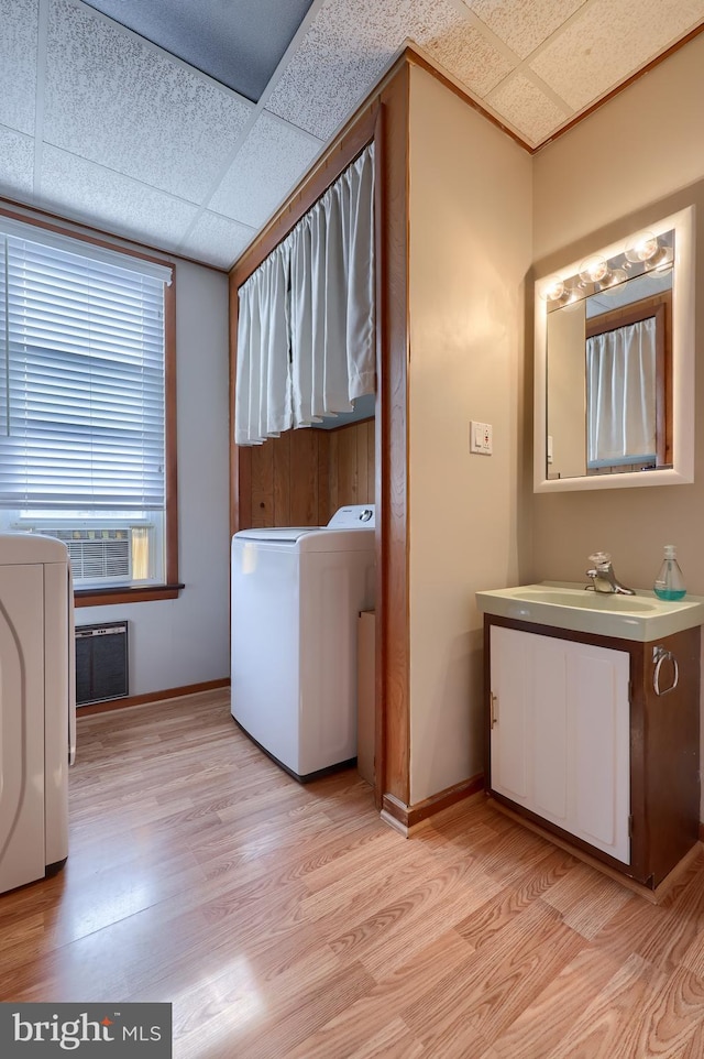 clothes washing area with sink, light hardwood / wood-style flooring, cabinets, and washer / dryer