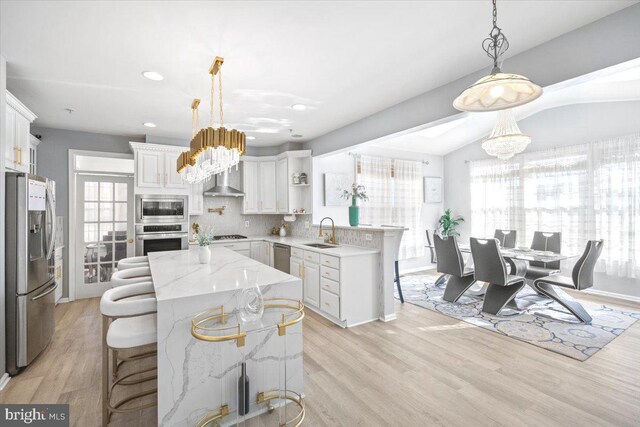 kitchen featuring sink, backsplash, appliances with stainless steel finishes, white cabinets, and light wood-type flooring