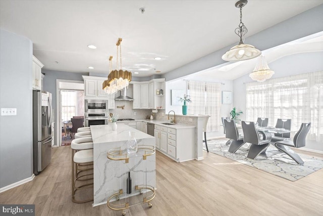 kitchen featuring white cabinetry, a kitchen breakfast bar, decorative backsplash, appliances with stainless steel finishes, and light wood-type flooring